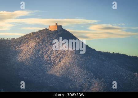 Vue de la forteresse médiévale Rocca Sillana, Pomarance, Val di Cecina, région de Toscane, Italie couronnant une colline enneigée et boisée illuminée par t Banque D'Images