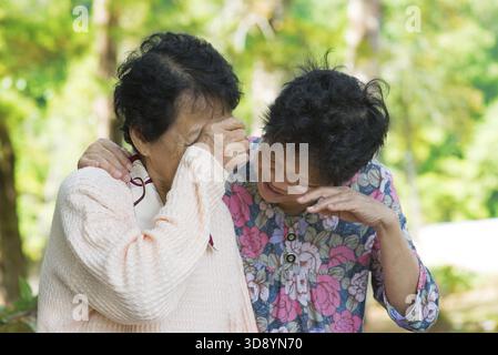 Tristes femmes asiatiques âgées dans le deuil de la perte d'un être cher. Parc extérieur Banque D'Images