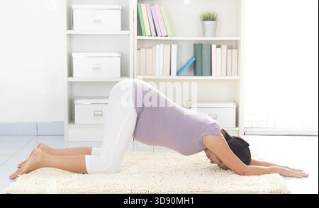 Méditation de yoga prénatale. Pleine longueur saine 8 mois enceinte calme femme asiatique méditant ou faisant de l'exercice de yoga à la maison Banque D'Images