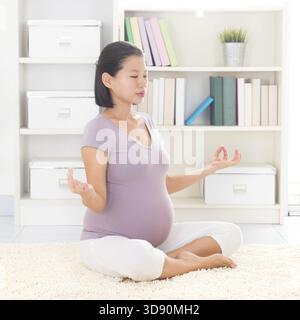 Méditation yoga grossesse. Pleine longueur saine 8 mois enceinte calme femme asiatique méditant ou faisant de l'exercice de yoga à la maison. Posture de yoga relaxation Banque D'Images