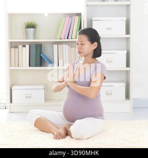 La grossesse yoga méditation. En bonne santé pleine longueur enceinte de 8 mois femme asiatique calme méditer ou faire de l'exercice de yoga à la maison. Positions de yoga relaxation Banque D'Images