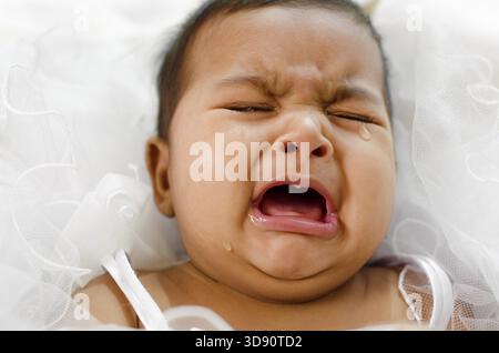 Pleurer Indian baby girl lying on bed Banque D'Images