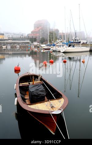 Bateau à moteur en bois amarré avec flotteurs de moteur couverts parmi les bouées rouges dans l'eau calme du port par un matin brumeux le long de la côte d'Helsinki, en Finlande. Banque D'Images