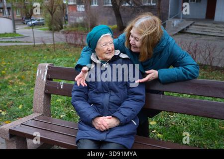 Deux dames âgées, mère et fille, marchent dans le parc un jour d'automne, parlant et riant. Banque D'Images