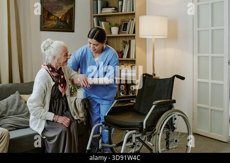 Infirmière d'âge moyen aidant une femme âgée handicapée Banque D'Images