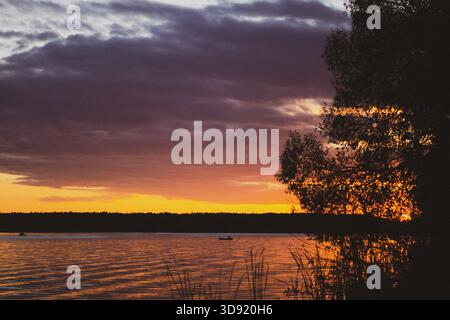 Coucher de soleil chaud, une large rivière, un pêcheur au loin Banque D'Images