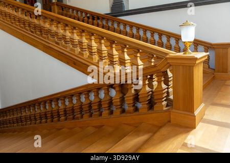 Les balustres en bois chauds forment un élégant motif répétitif le long de l'escalier dans la lumière du jour douce. Les surfaces lisses et les détails travaillés créent une atmosphère raffinée Banque D'Images