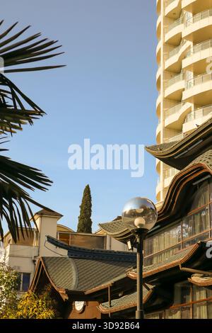 Scène urbaine mêlant architecture orientale traditionnelle et gratte-ciel moderne, notamment lanterne et plantes exotiques sous la lumière du soleil. Banque D'Images