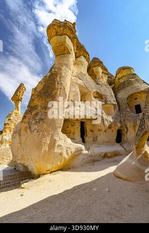 Vue des formations rocheuses imposantes sous un ciel bleu vif, avec des entrées sculptées et des surfaces texturées, créant un paysage surréaliste, Zelve, Cappadoce Banque D'Images