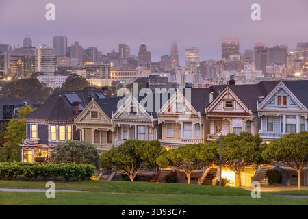 Les maisons Painted Ladies près d'Alamo Square à l'aube, avec la ville de San Francisco émergeant du brouillard du matin, Californie, États-Unis. Été (août) 2025. Banque D'Images