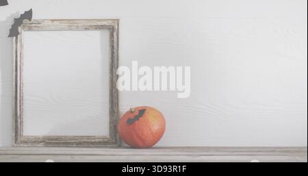 Affichage de la petite citrouille orange assise sur le dessus de table usé avec le cadre et les découpes de chauve-souris, espace de copie Banque D'Images