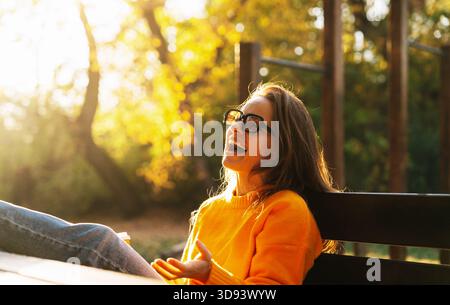 Jeune femme riant tout en prenant une pause dans le parc d'automne Banque D'Images