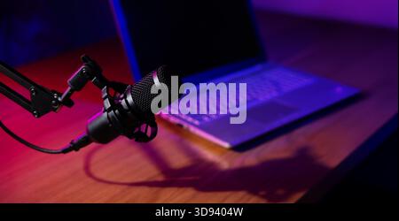 enregistrement, streaming et diffusion de podcasts. microphone avec ordinateur portable sur la table en studio avec néons. bannière avec espace de copie Banque D'Images