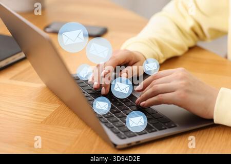 Femme envoyant ou recevant un courriel sur ordinateur portable à table, gros plan. Lettres qui volent hors de l'écran Banque D'Images