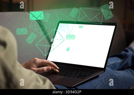 Femme envoyant ou recevant des e-mails sur ordinateur portable à la maison, gros plan. Lettres qui volent hors de l'écran Banque D'Images