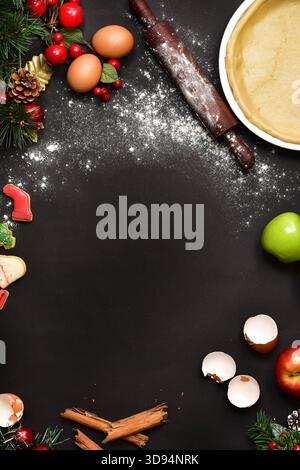 Une couche plate de haut en bas, sombre et festive montrant le processus de cuisson des fêtes, avec un cadre central de farine dispersée, entouré d'ingrédients, un bois Banque D'Images