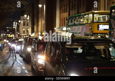 Dublin, Irlande - 03 décembre 2025 - Une file de taxis sur une route le long des quais alors que les chauffeurs de taxi de Dublin organisent une manifestation « Go slow » aux heures de pointe pour protester contre les nouveaux tarifs fixes d'Uber avec des retards dans la circulation dans la capitale irlandaise Banque D'Images