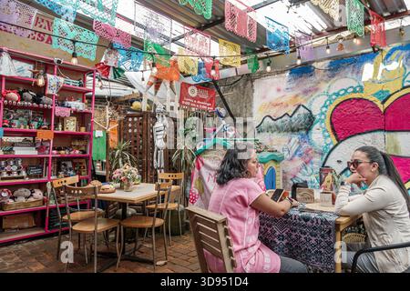 Mexico City Mexique, Xochimilco, Dalia restaurant café, femmes hispaniques adultes latino assis parlant à la table, patio extérieur papel picado décor, étagère artisanale Banque D'Images