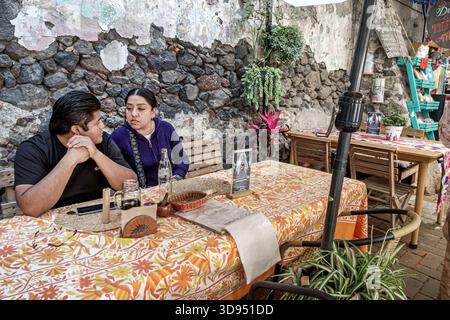 Mexico City Mexique, Xochimilco, Dalia restaurant café, hispanique Latino couple homme femme adultes parlant assis à table, verre de bouteille de boissons, mur de pierre rus Banque D'Images
