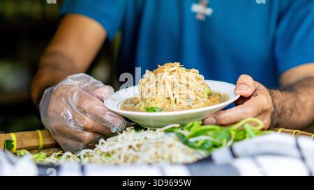 Acheteur au service du pecel. Pecel est une salade javanaise traditionnelle composée de légumes bouillis arrosés de sauce aux arachides Banque D'Images