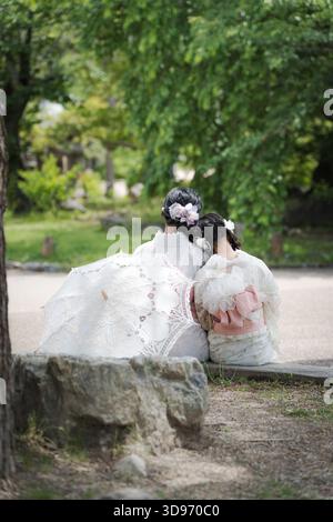 Deux femmes portant des kimonos en dentelle blanche assis sur le trottoir avec parasol en dentelle. Kyoto, Japon. Banque D'Images
