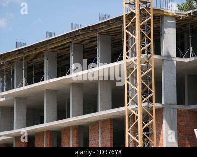 Vue détaillée d'un bâtiment à ossature monolithique en cours de construction, avec des murs de briques apparentes et une ossature structurelle Banque D'Images