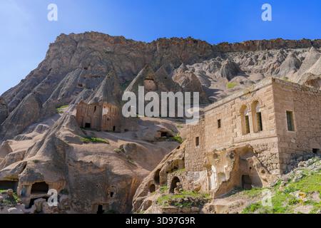 Vue sur les anciennes habitations sculptées dans les formations rocheuses molles sous un ciel bleu vibrant, où l'histoire murmure de chaque pierre, Selime, Türkiye. Banque D'Images