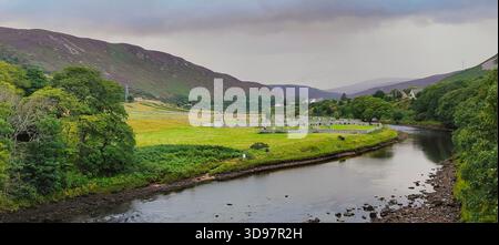 Une vue paisible sur la rivière Helmsdale qui coule à côté d'un vieux cimetière niché dans le paysage verdoyant luxuriant de l'Écosse rurale Banque D'Images