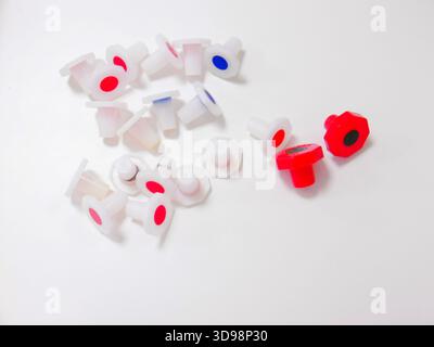 Chapeaux en plastique rouge et bleu dispersés sur fond blanc, StudioLit minimaliste Still Life Showelling Assembly Banque D'Images