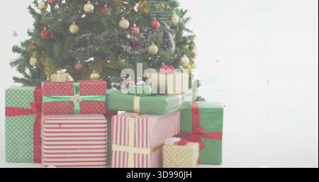 Affichage de l'arbre de Noël décoré debout à gauche dans la pièce blanche, montrant des cadeaux emballés avec des rubans Banque D'Images