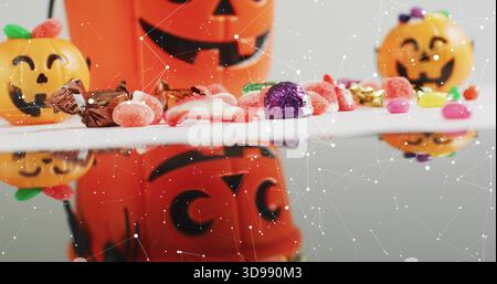 Affichage d'une rangée de bonbons et de petits seaux de citrouille sur une table brillante, avec recouvrement translucide Banque D'Images