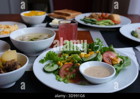 Un repas magnifiquement présenté comprend des brocolis tendres, des boulettes salées et de la salade fraîche, parfaitement disposés sur une table élégante dans une ambiance chaleureuse au crépuscule. Photo de haute qualité Banque D'Images