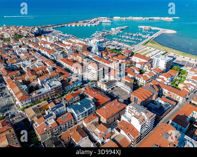 Vue aérienne des toits en terre cuite en cascade vers la mer Azur, avec les bateaux du port qui bougent doucement, Termoli, Molise, Italie. Banque D'Images