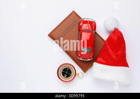 Vacances de Noël. Passeport, modèle de voiture, chapeau de Santa et boussole sur fond blanc, pose plate. Espace pour le texte Banque D'Images