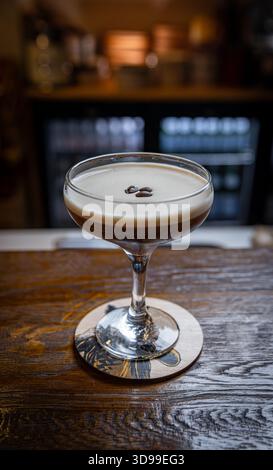 Martini espresso avec une couche de mousse crémeuse servi dans un verre coupé sur une barre en bois Banque D'Images