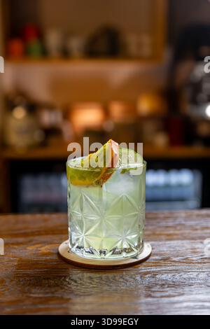 Cocktail à l'ancienne avec whisky, glace, décoré avec tranche de kiwano sur un bar en bois Banque D'Images