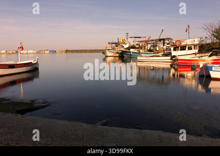 Bateaux de pêche dans le port calme au coucher du soleil avec l'eau lisse. Plusieurs bateaux colorés sont amarrés dans une marina paisible, avec une lumière douce heure dorée, pas Banque D'Images