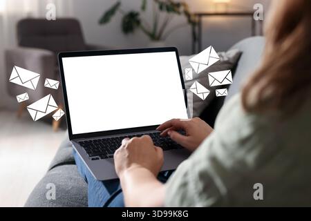 Femme envoyant ou recevant des e-mails sur ordinateur portable à la maison, gros plan. Lettres qui volent hors de l'écran Banque D'Images