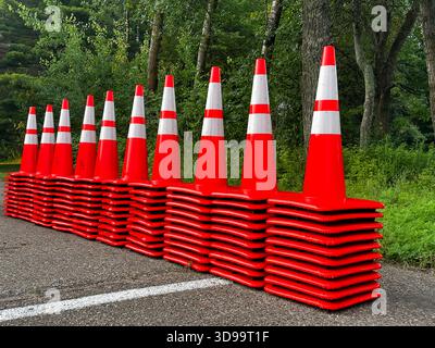 Dix pointes de cônes de circulation en plastique orange et blanc alignés en une rangée. Banque D'Images