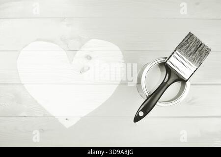 Peindre la boîte et le pinceau reposant sur des planches de bois avec une forme de coeur peinte à la main. Concepts d'amour, de bricolage et d'amélioration de la maison. Couleur de 2026 ans danseur i Banque D'Images