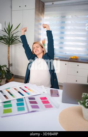 Femme enceinte qui s'étire tout en travaillant à domicile Banque D'Images