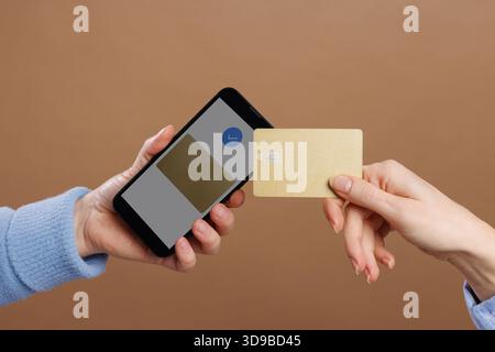 La main de la femme avec la carte bancaire apporte au smartphone, fait le paiement sans contact, NFC. Banque D'Images