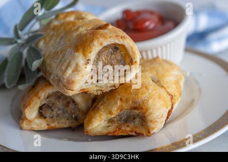 Rouleaux de saucisse faits maison avec de la pâte feuilletée à volants maison et de la viande de saucisse avec un plat de ketchup de tomate pour tremper. Noël britannique traditionnel Banque D'Images