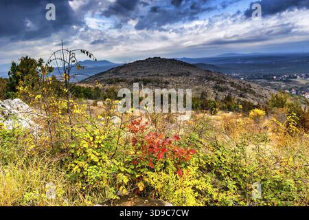 Voir l'automne de la Croix (Krizevac) Mountain à Medjugorje en Bosnie Erzegovina ed : arbres brunâtre, mauvaises herbes vertes, orange et des feuilles jaunes et gris roc Banque D'Images