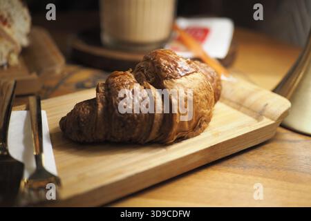 Croissant fraîchement cuit sur une planche de bois dans un café Banque D'Images