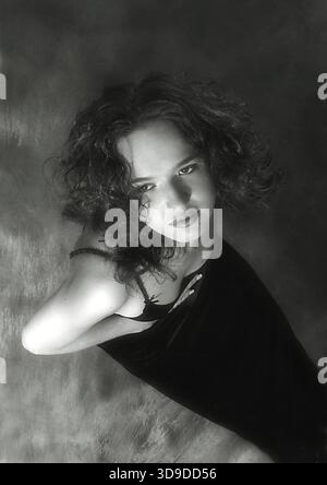 Portrait de l'harmonous fille dans une robe noire sur un fond sombre. b/w Banque D'Images