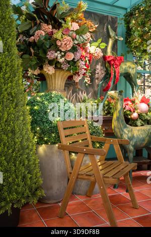 Une scène de jardin extérieur confortable avec une chaise en bois, des bouquets de fleurs vibrants, une végétation luxuriante et des statues décoratives, parfait pour la décoration de jardin Banque D'Images