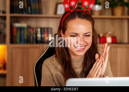 Portrait de femme heureuse dans le bandeau de bois de renne lors de la réunion virtuelle de Noël avec la famille Banque D'Images