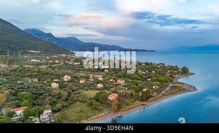 Vue aérienne par drone de Marathias, un village côtier en Grèce centrale, montrant le golfe de Corinthe rivage, la mer bleue claire, les maisons traditionnelles. Banque D'Images