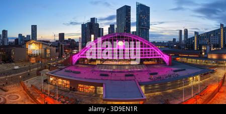 Vue aérienne au crépuscule de Manchester Central (GMEX) avec son éclairage rose, contre les tours de Deansgate Square et les gratte-ciel de la ville en hiver. Banque D'Images